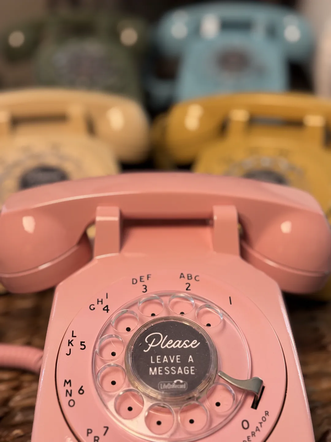 Close view of a pink LifeOnRecord rotary phone with colorful phones behind it
