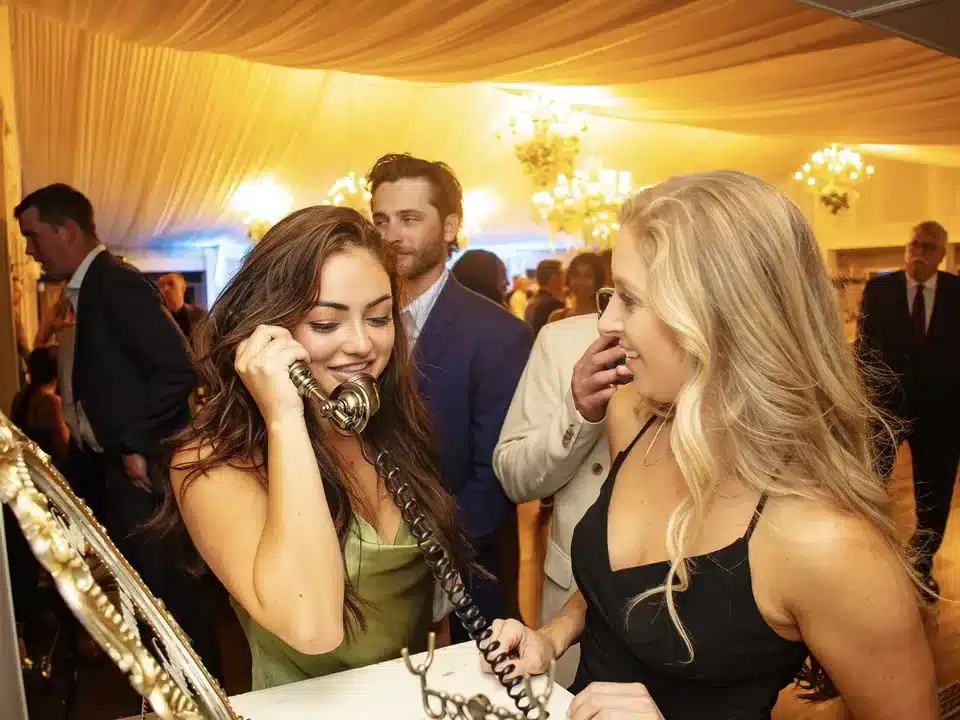 Wedding guests laughing together while leaving a message on a vintage telephone