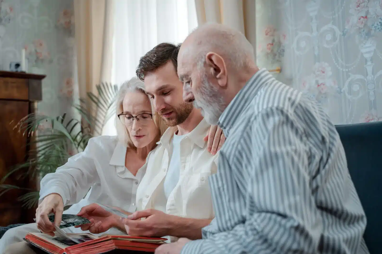 Three family members of different generations looking through old photographs together